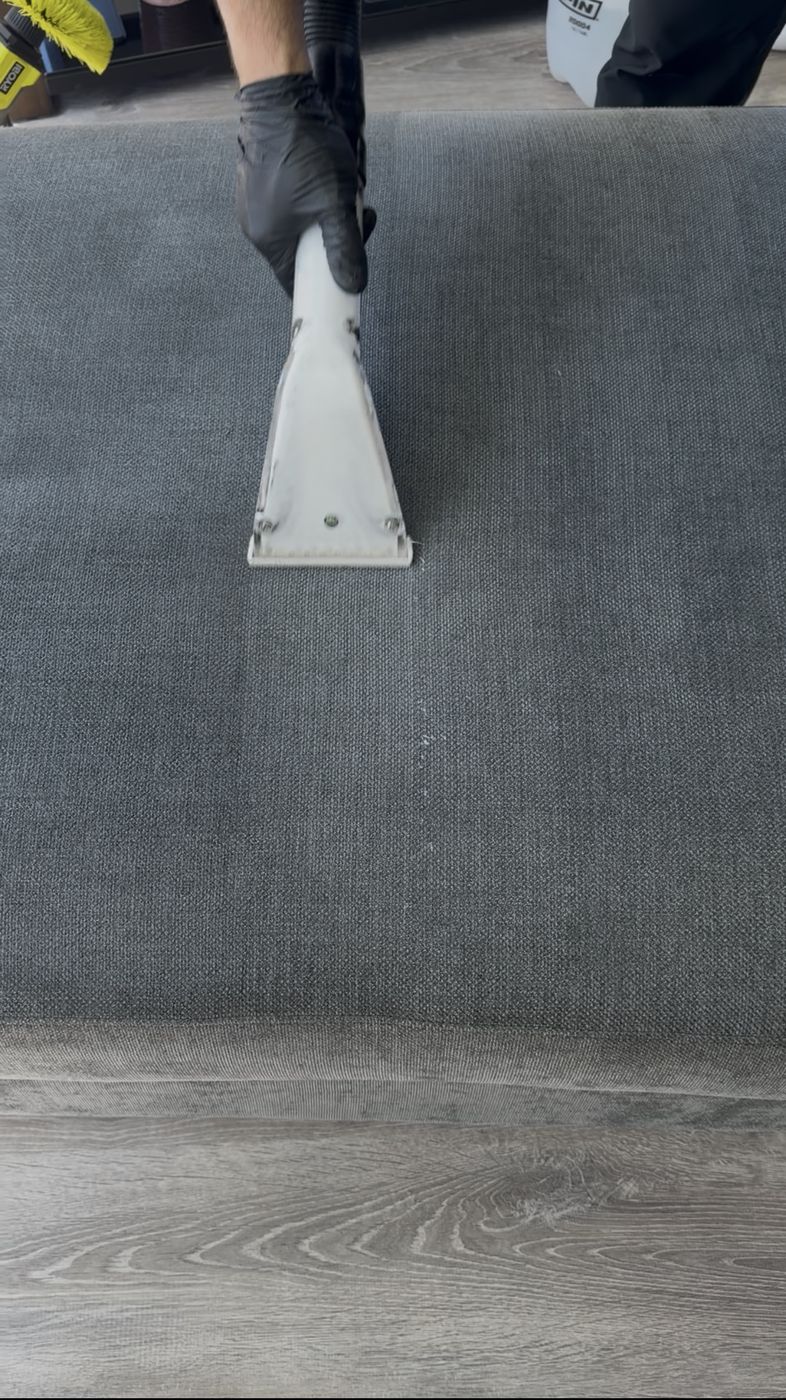 Dark gray ottoman with visible clean stripe during deep cleaning
